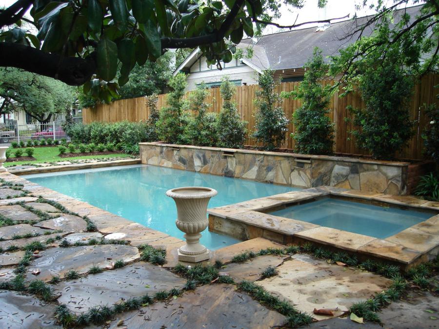 Outdoor pool with multi colored edge stonework and stone garden background.