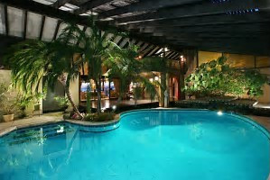 Square outdoor pool and hot tub lined with stone walkways and grass filled gaps.