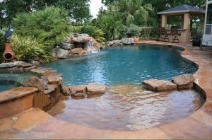 Minimalistic spa type pool with dark wood and black stone surroundings.