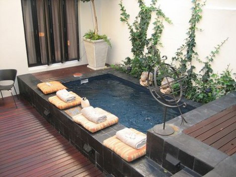 Outdoor pool with palms and stone textured, screened enclosure.