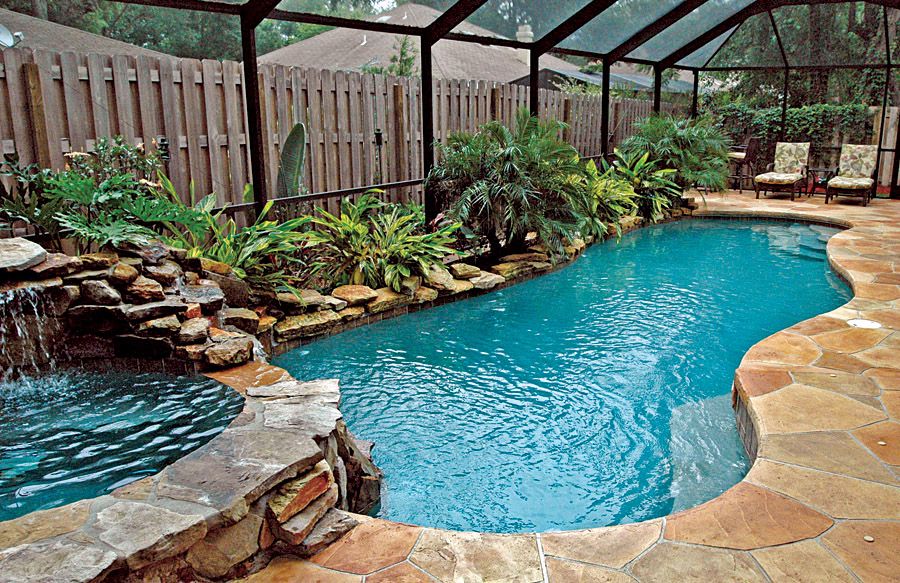 Two tier outdoor pool with hot tub, palm trees and stone texture surroundings.